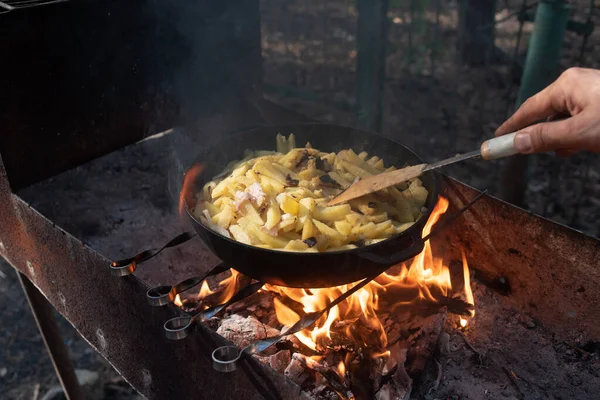 Hot big wok pan full of fried tasty potato on the fire in the forest