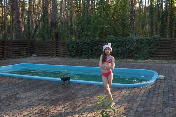 Ett barn leker med en jultomte hatt. Lycklig liten flicka i jultomten hatt utomhus på sommaren. — Stockfoto