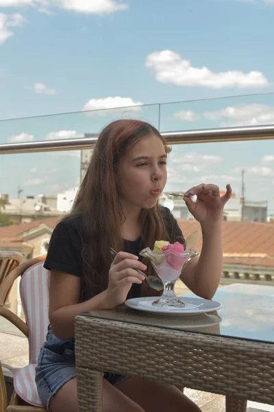 Hermosa mujer joven feliz sonriendo, mirando a la cámara sentada en el restaurante o cafetería y comiendo helado — Foto de Stock
