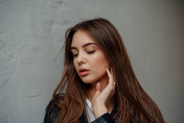 Siyah deri ceketli genç bir kız şehrin arka planında duruyor..