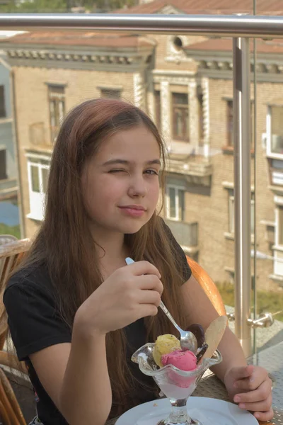 Belle jeune femme souriante heureuse, regardant la caméra assise dans un restaurant ou un café et mangeant de la crème glacée — Photo