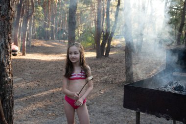 Ahşap şişler üzerinde yumuşar, ahşap alevler üzerinde kızarır. Kız kazıkta lokum pişiriyor.