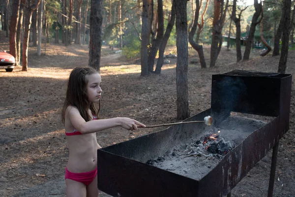 Mlaștina se topește pe frigărui de lemn prăjind peste flăcările lemnului. Fata gătește bezele pe rug — Fotografie, imagine de stoc
