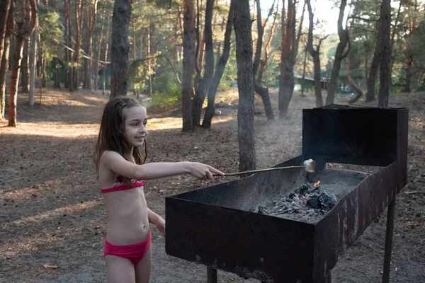 Pantano suave en pinchos de madera tostado sobre llamas de madera. Chica cocina malvaviscos en la hoguera —  Fotos de Stock
