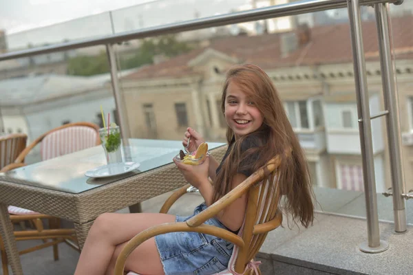 Belle jeune femme souriante heureuse, regardant la caméra assise dans un restaurant ou un café et mangeant de la crème glacée — Photo