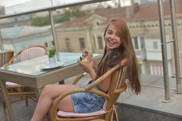 Belle jeune femme souriante heureuse, regardant la caméra assise dans un restaurant ou un café et mangeant de la crème glacée — Photo