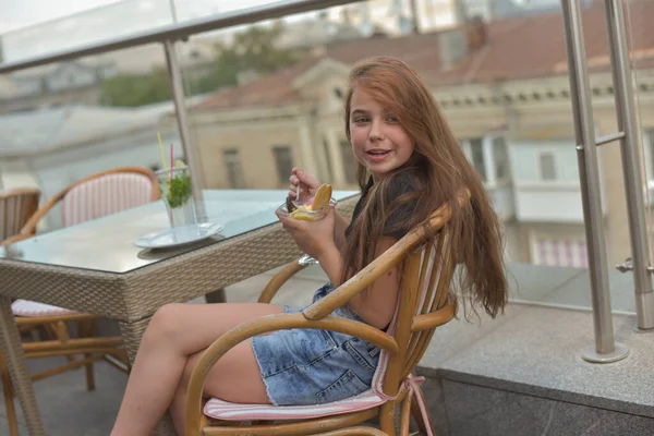 Belle jeune femme souriante heureuse, regardant la caméra assise dans un restaurant ou un café et mangeant de la crème glacée — Photo