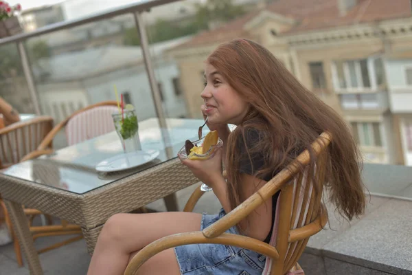 Belle jeune femme souriante heureuse, regardant la caméra assise dans un restaurant ou un café et mangeant de la crème glacée — Photo