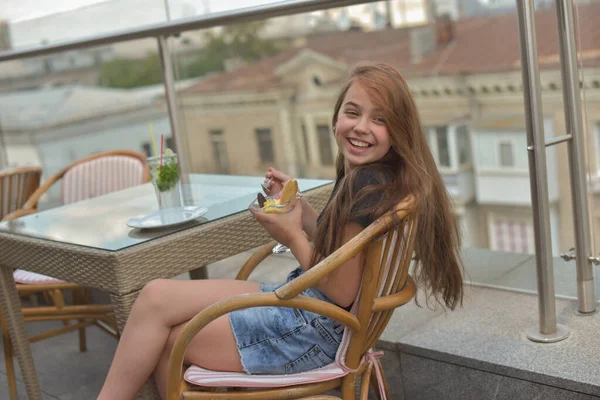 Belle jeune femme souriante heureuse, regardant la caméra assise dans un restaurant ou un café et mangeant de la crème glacée — Photo