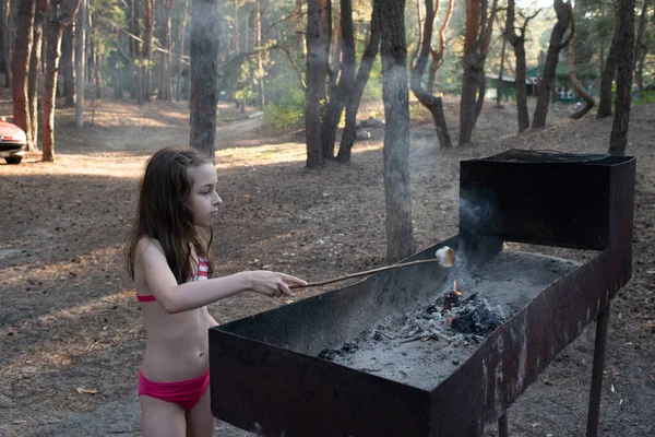 Mlaștina se topește pe frigărui de lemn prăjind peste flăcările lemnului. Fata gătește bezele pe rug — Fotografie, imagine de stoc