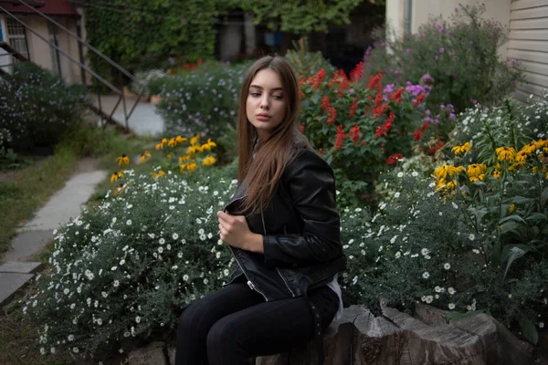 Ung flicka i en svart läderjacka står på bakgrunden av en stad street.Girl i en läderjacka — Stockfoto