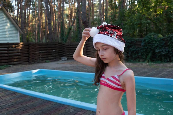 子供がサンタクロースの帽子をかぶって遊んでいる。夏に屋外サンタクロース帽子で幸せな小さな女の子. — ストック写真