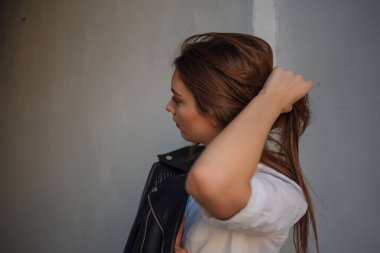 Siyah deri ceketli genç bir kız şehrin arka planında duruyor..