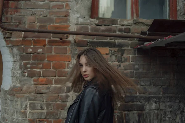 Ung flicka i svart läder jacka står på bakgrunden av en stad gata. — Stockfoto
