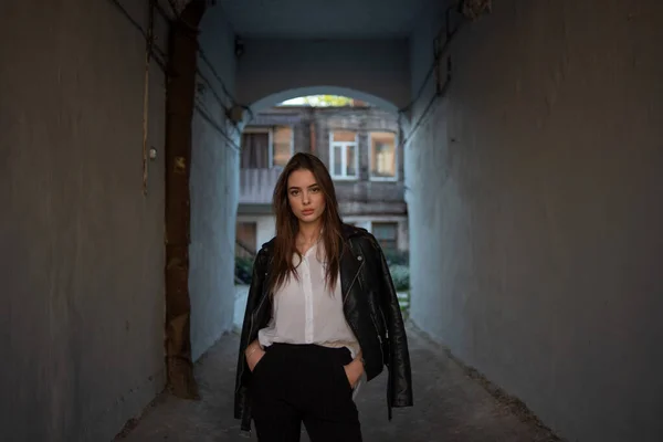 Ung flicka i svart läder jacka står på bakgrunden av en stad gata. — Stockfoto