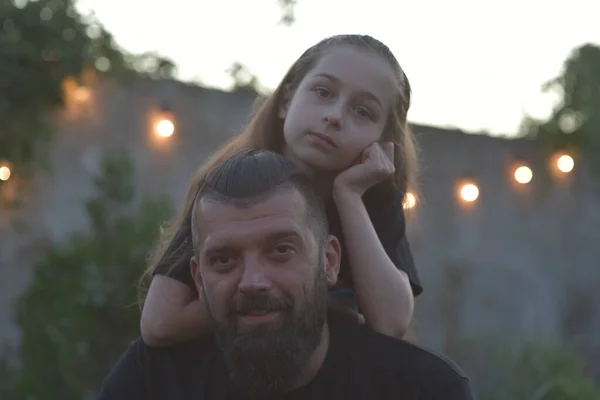 Family time. Little girl hugging her dad with a beard. Summer walk. Child girl with blond hair rejoices with a parent.