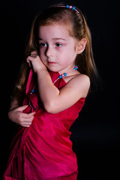 Menina pequena bonita child.Little posando no estúdio com um pano em um fundo preto — Fotografia de Stock