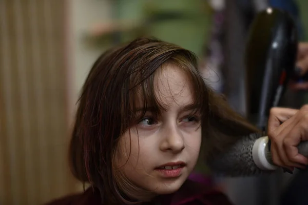Coiffeur styliste fait une coiffure pour une petite fille mignonne dans un salon de beauté. — Photo