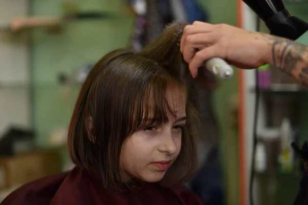 Стиліст перукар робить зачіску для милої маленької дівчинки в салоні краси . — стокове фото