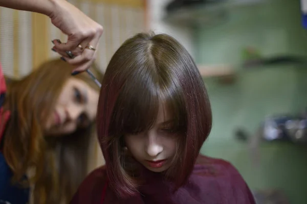 Stylist fodrász teszi a frizura egy aranyos kislány egy szépségszalonban. — Stock Fotó