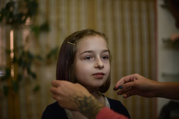 Cabeleireiro estilista faz um penteado para uma menina bonito em um salão de beleza. — Fotografia de Stock