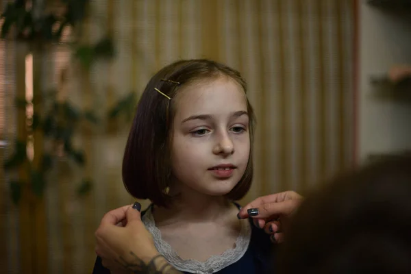 Cabeleireiro estilista faz um penteado para uma menina bonito em um salão de beleza. — Fotografia de Stock