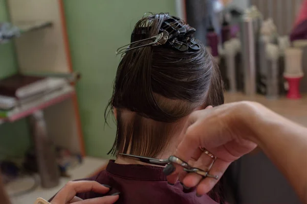 Cabeleireiro estilista faz um penteado para uma menina bonito em um salão de beleza. — Fotografia de Stock