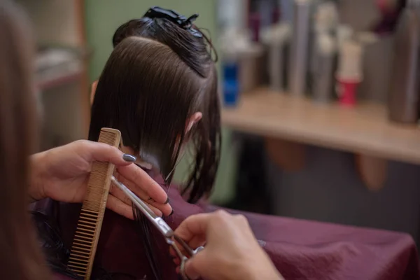 Stylist Friseur macht eine Frisur für ein süßes kleines Mädchen in einem Schönheitssalon. — Stockfoto