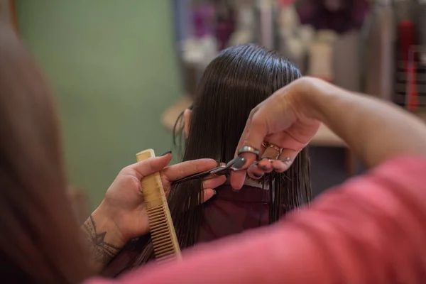 Cabeleireiro estilista faz um penteado para uma menina bonito em um salão de beleza. — Fotografia de Stock