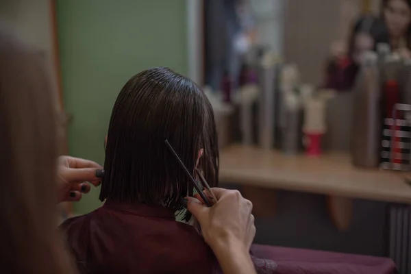 Stylist hairdresser makes a hairstyle for a cute little girl in a beauty salon. — Stock Photo, Image