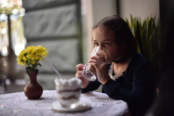 Маленька дівчинка п'є гарячий шоколад у кафе — стокове фото