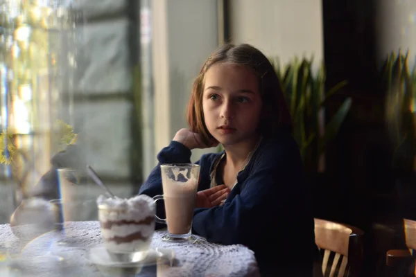 Klein meisje dat warme chocolademelk drinkt in een café — Stockfoto