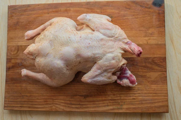 Pollo intero crudo biologico su sfondo rustico in legno — Foto Stock
