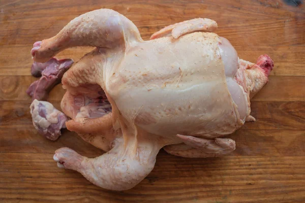 Pollo intero crudo biologico su sfondo rustico in legno — Foto Stock