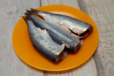 Tuz, biber, otlar ve beyaz arka plan üzerinde beyaz seramik plaka üzerinde limon ile ringa balığı