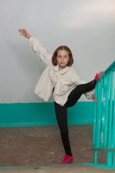 European sporty girl in casual clothes showing vertical twine outdoor. Stretching training.