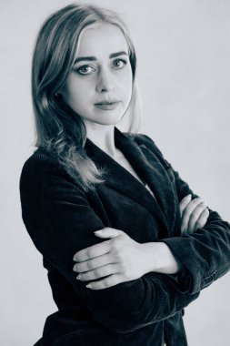 Beyaz bir duvara yaslanmış zarif genç bir kadın. Beyaz bir duvara karşı klasik ceketli bir kadın. Beyaz bir duvarın yanında poz veren zarif genç bir kadın. Ofis tarzı. Kendine güvenen kadın.