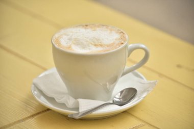 Bir fincan kahve, beyaz bir fincanda bir fincan kapuçino. Masadaki kafede kahve.