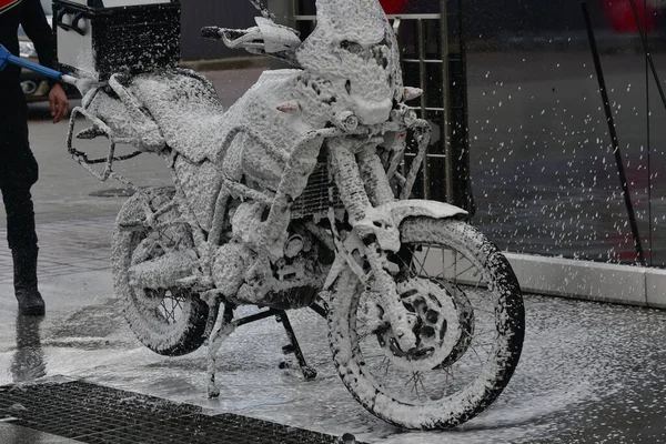 Motorcycle washing with cleaning foam. Pure moto bike. Enduro motorcycle. Cleanliness of vehicles. Car wash professional. Transportation concept. Vehicle wash. A series of photos of a motorcycle.