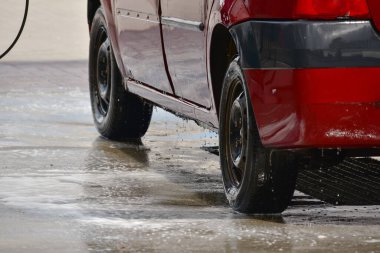 Yıkama sırasında kırmızı araba. Oto yıkamada köpüklü taşıma, dışarıda araba yıkamada basınçlı su ile elle yıkama. Yaz Yıkama. Yüksek Basınçlı Su Kullanımı Temizleniyor.