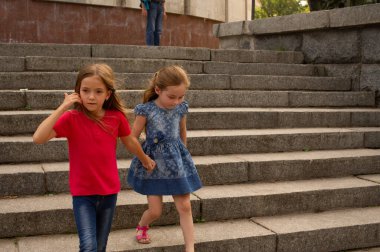 Kız kardeşler, iki küçük kızın açık hava fotoğrafı. Parkta iki küçük kız el ele yürür. Kardeşler yazın ya da sonbaharda sokakta yürüyüşe çıkarlar. Kız arkadaşlar, çocuklar, doğa. Aile kavramı.