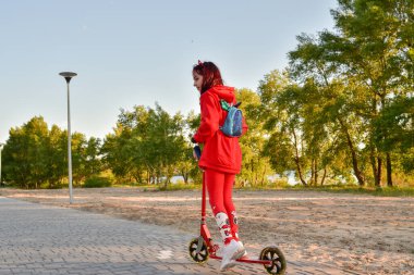 Mobilete binen çocuk. Renkli tekme tahtasında bir çocuk. Çocuklar için açık hava eğlencesi. Çocuklar için spor. Spring Park 'taki küçük mutlu kız. Sağlıklı bir yaşam tarzı. Çevre dostu nakliye aracı. Mobiletli bir genç.