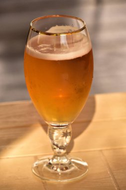 Masada bira var. Tahta masada bir bardak light bira. Bira ahşap masada bulanık şehir parkı arka planda, doğal arka planda Bokeh ile birlikte.