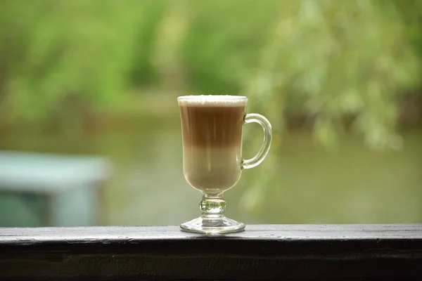 Hot coffee on the summer terrace. Warm weather. Cup of latte in the summer. Cappuccino or latte in a summer cafe