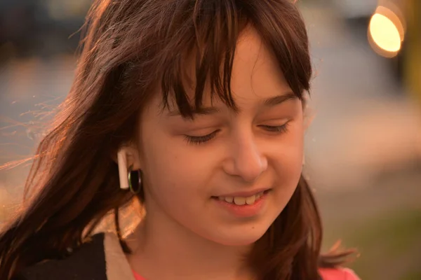 소녀가 헤드폰으로 미소를 짓습니다 여름에 살짜리 선셋의 거리에서 — 스톡 사진