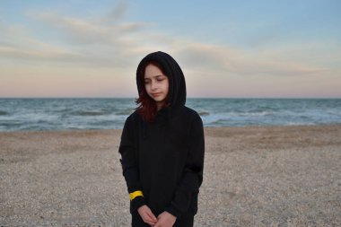 Gün batımında deniz kenarında şık ceketli bir mankenin portresi. Siyah kapüşonlu bir genç ve deniz. İnsan ve deniz. Yazın gün batımında, deniz kenarında kapüşonlu bir kız. 9 yaşında bir kız..