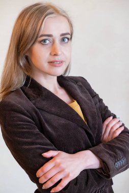 Beyaz bir duvara yaslanmış zarif genç bir kadın. Beyaz bir duvara karşı klasik ceketli bir kadın. Beyaz bir duvarın yanında poz veren zarif genç bir kadın. Ofis tarzı. Kendine güvenen kadın.