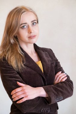 Beyaz bir duvara yaslanmış zarif genç bir kadın. Beyaz bir duvara karşı klasik ceketli bir kadın. Beyaz bir duvarın yanında poz veren zarif genç bir kadın. Ofis tarzı. Kendine güvenen kadın.