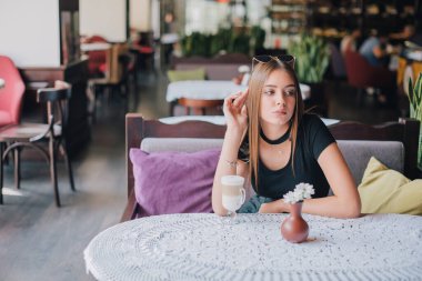 Sabahları restoranda kahve içen bir kadın. Kapuçinolu güzel bir kız. Neşeli bayan keyfine bak ve rahatla. Kafede bir fincan latte içen bir kız. Esmer portresi