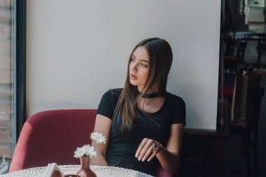 Çok güzel bir bayan keyfine bak ve rahatla. Kafedeki kız. Esmer portresi. Siyah elbise dükkanındaki kız. Genç bir kız beklerken pencereden dışarı bakar. Beklenti. Umut. Güzellik konsepti